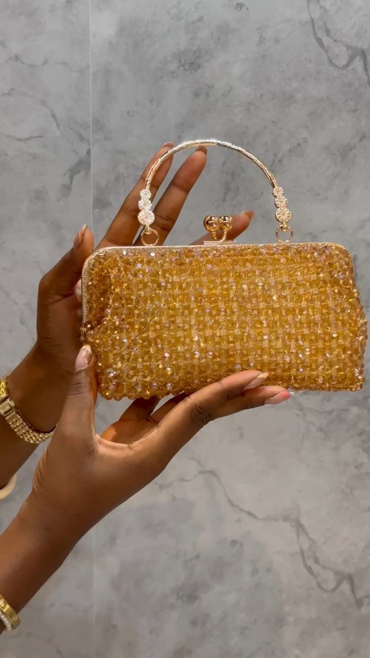 A champagne crystal-beaded clutch, held to the light